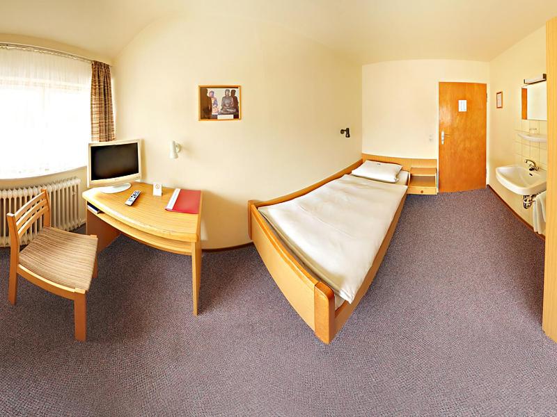 ein Hotelzimmer mit einem Bett, einem Schreibtisch und einem Tisch in der Unterkunft Pension Keinath in Stuttgart