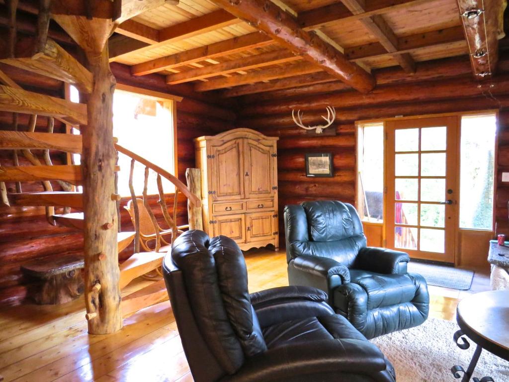 a living room with leather furniture in a log cabin at Handsome Dan's at Otter Point in Sooke