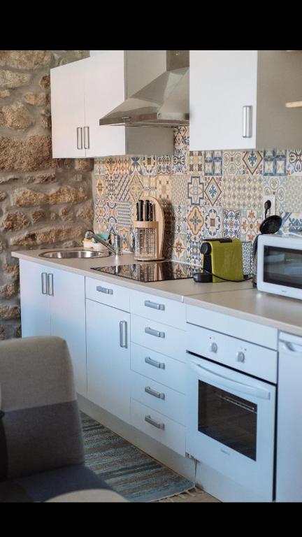 a kitchen with white cabinets and a microwave at Casa da Chã! in Chã