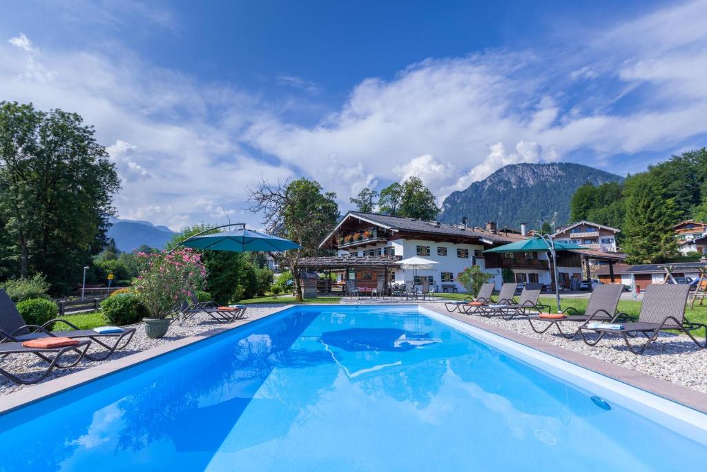 a pool at a resort with mountains in the background at Gästehaus und Ferienwohnungen Egglerlehen in Schönau am Königssee