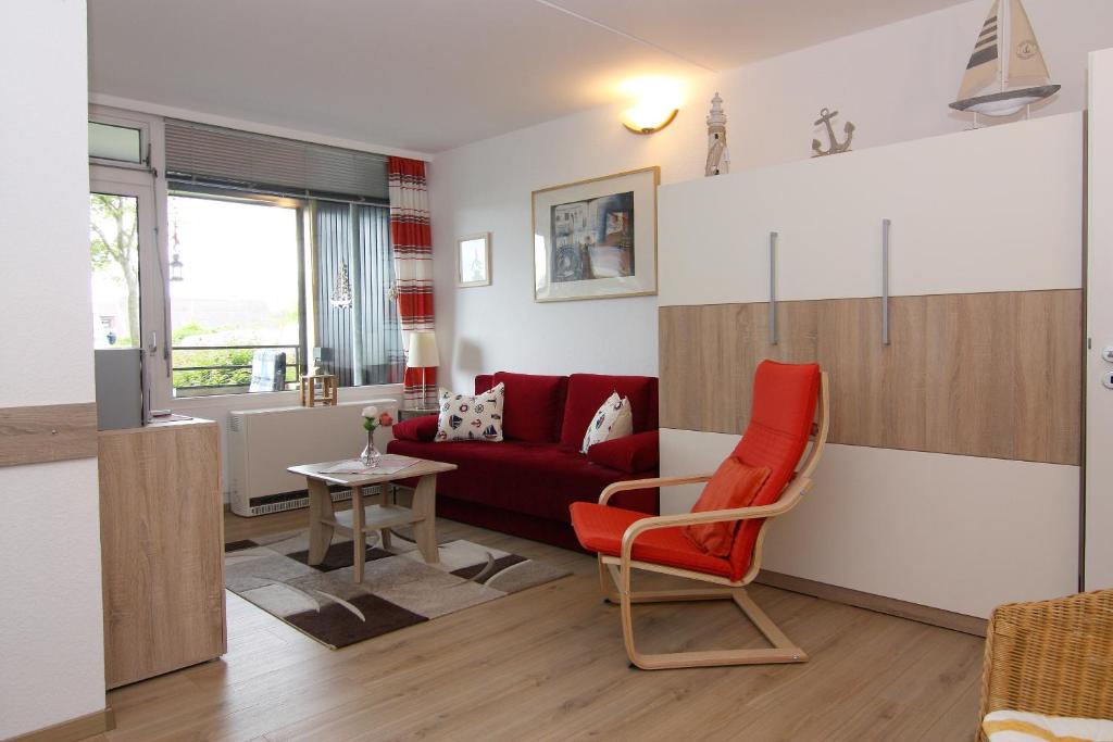 ein Wohnzimmer mit einem roten Sofa und einem Tisch in der Unterkunft Ferienwohnung Marina Wendtorf App. 6110 in Wendtorf