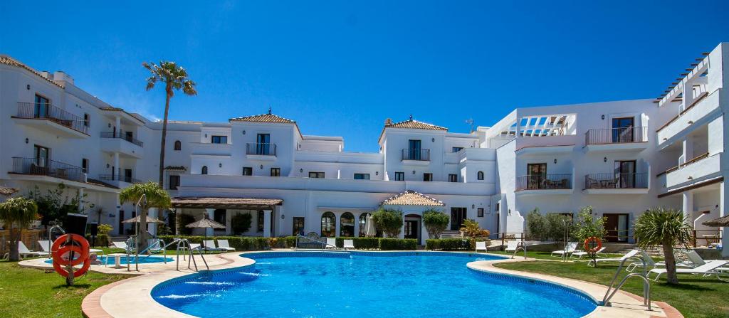 un hotel con piscina frente a un edificio en Hotel Doña Lola Zahara en Zahara de los Atunes