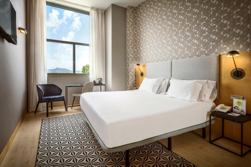 um quarto de hotel com uma grande cama branca e uma secretária em Hotel Sercotel Portales em Logroño