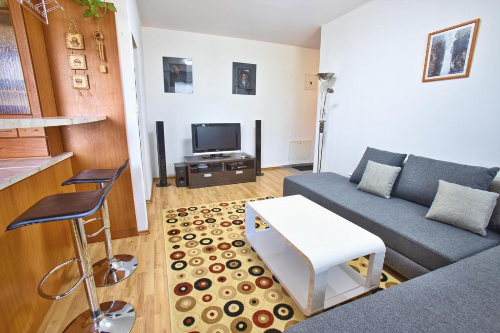 uma sala de estar com um sofá e uma televisão em Apartman Hugo em Veľký Slavkov