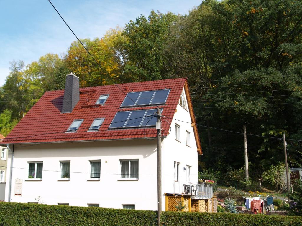 una casa con techo rojo con paneles solares. en Ferienwohnung Richter, en Tharandt