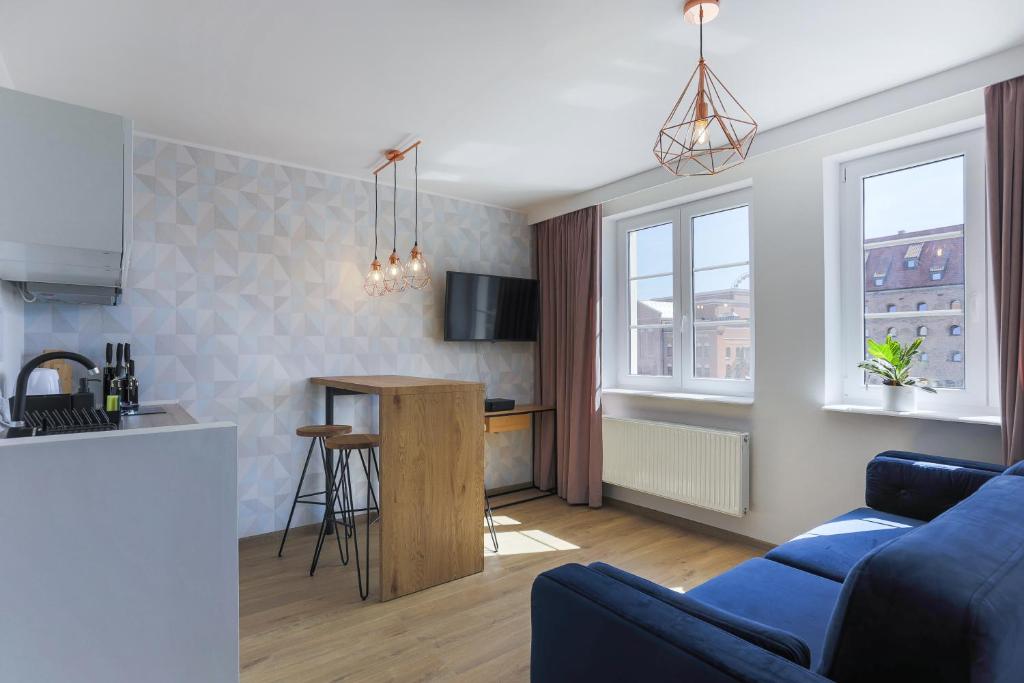 ein Wohnzimmer mit einem blauen Sofa und einer Küche in der Unterkunft Apartament IGO OLD TOWN in Danzig