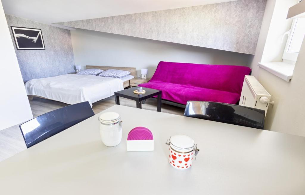 a living room with a pink couch and a bed at Apartmán Theo in Veľký Slavkov