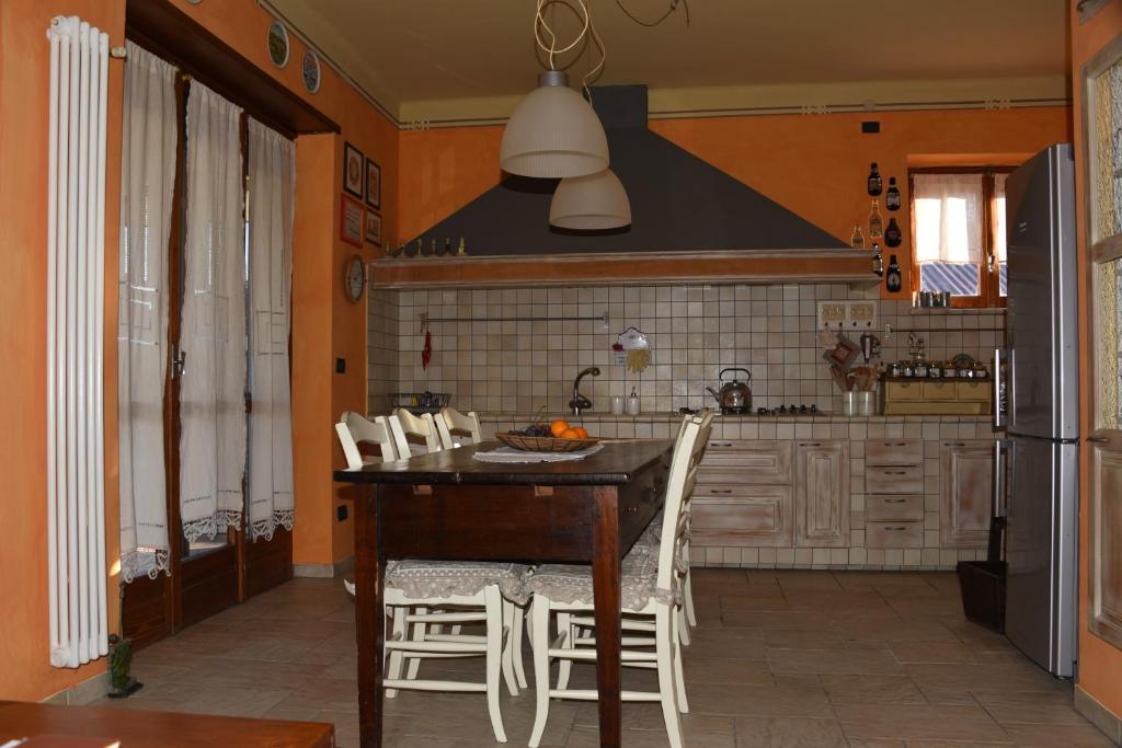 een keuken met een houten tafel en witte stoelen bij Ca' Mia Ca' Tua in La Loggia