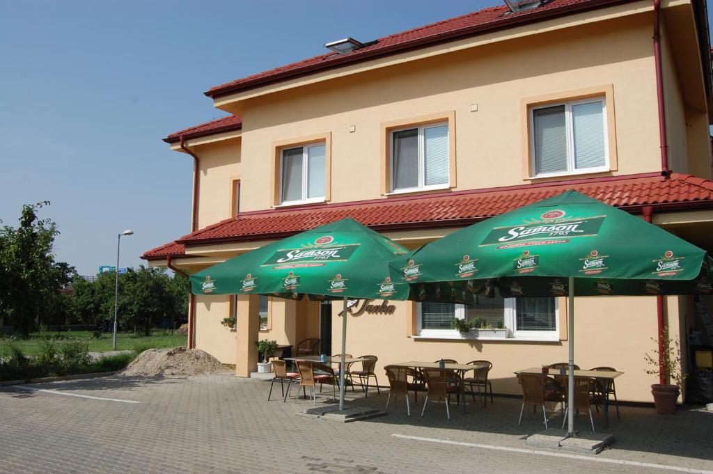 two green umbrellas and tables and chairs in front of a building at Penzion Jarka in Bratislava