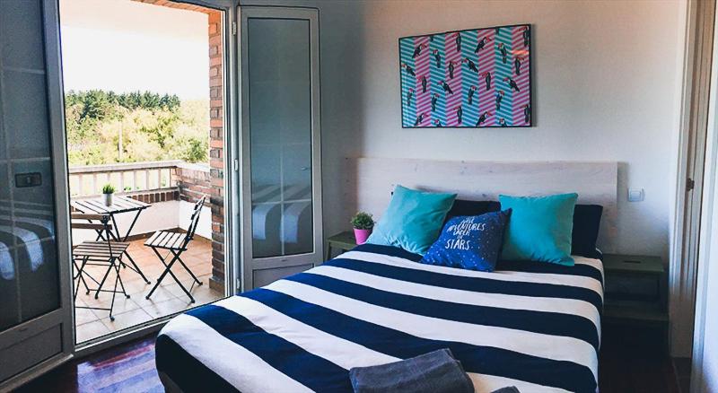 a bedroom with a bed and a balcony with a table at Loredo Surf House in Loredo