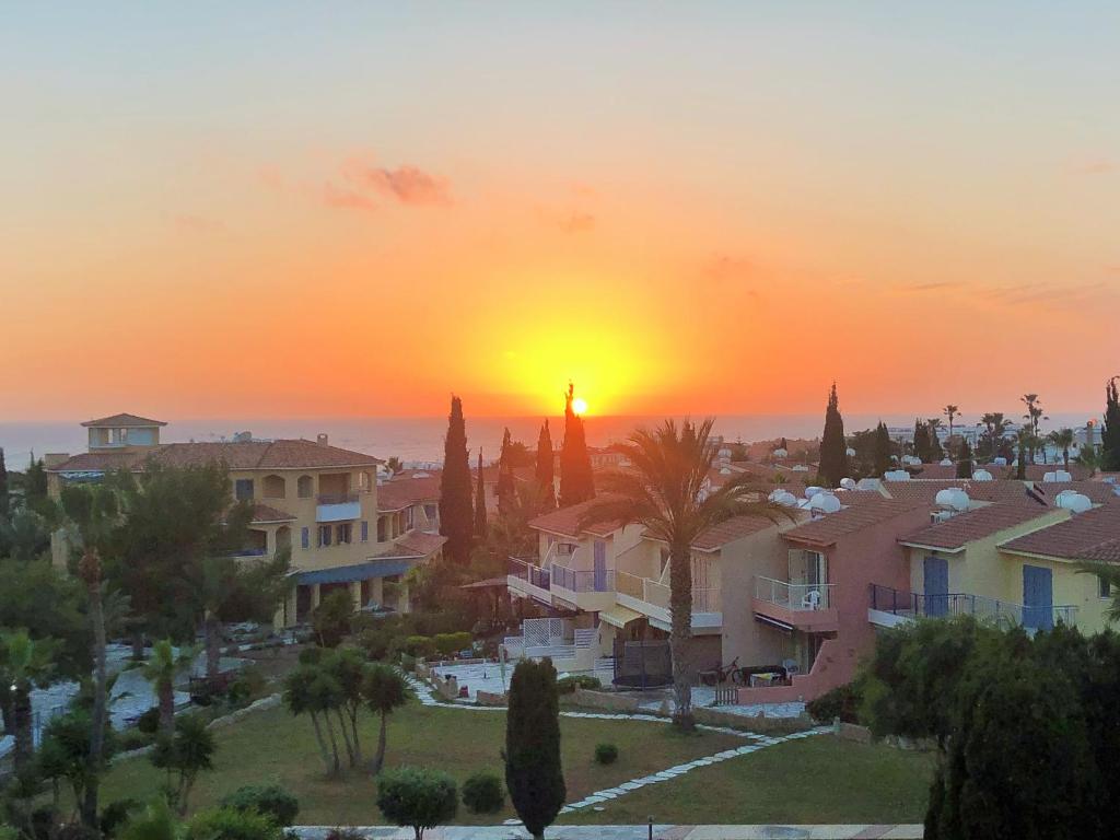 una puesta de sol sobre una ciudad con casas y palmeras en Regina Gardens, Phase 1 (Sea View) en Pafos