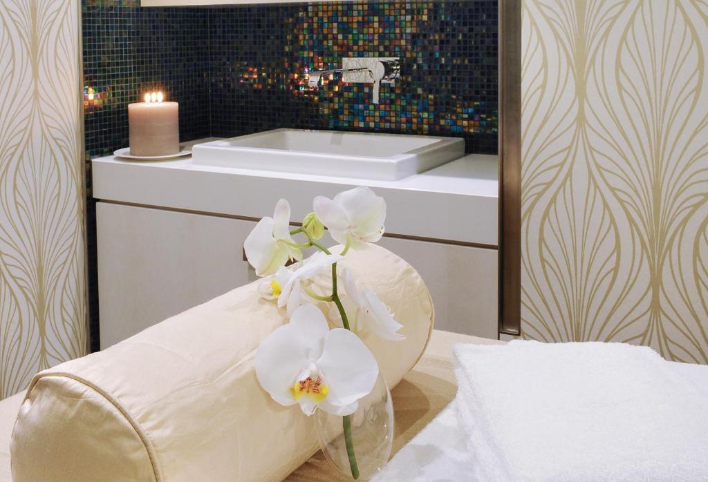 a bathroom with a vase with white flowers in it at Hôtel Tiffany by Fassbind in Geneva