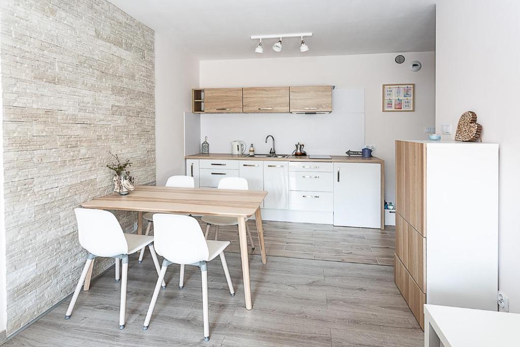 kuchnia z drewnianym stołem i białymi krzesłami w obiekcie Apartament Kasia w mieście Karpacz
