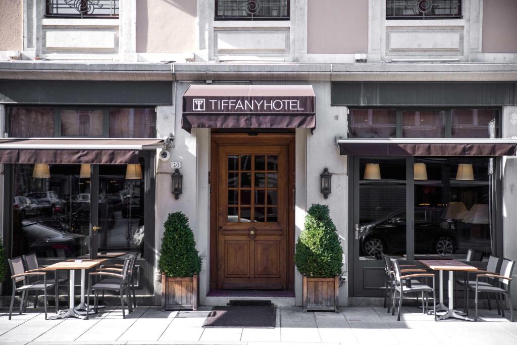 a restaurant with tables and chairs in front of a door at Hôtel Tiffany by Fassbind in Geneva