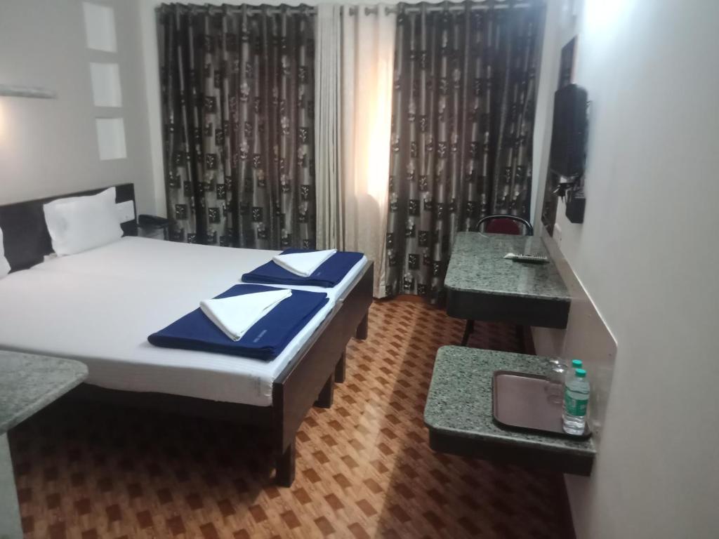 a bedroom with a bed and two tables and a television at Hotel Hanuman in Mangalore