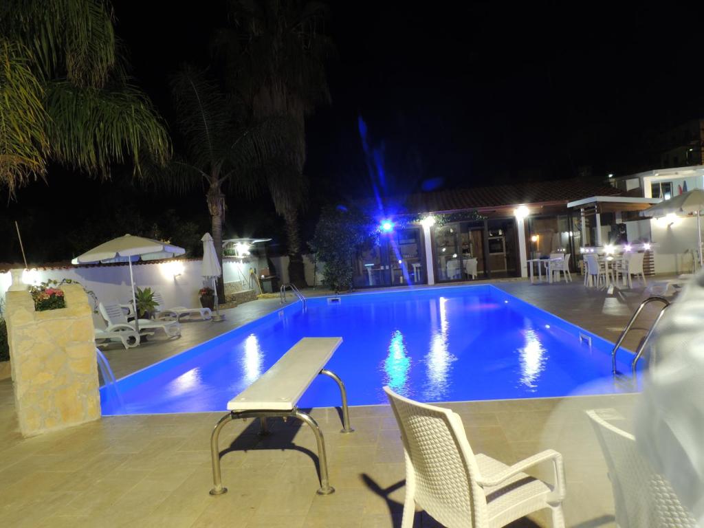 einen Pool in der Nacht mit einem Tisch und Stühlen in der Unterkunft All'Ombra Del Noce B&B in Catona