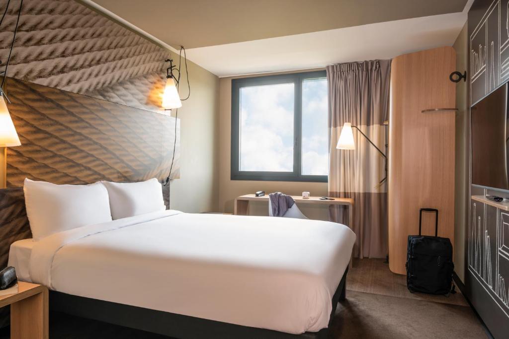 a hotel room with a large bed and a window at ibis Gonesse in Gonesse