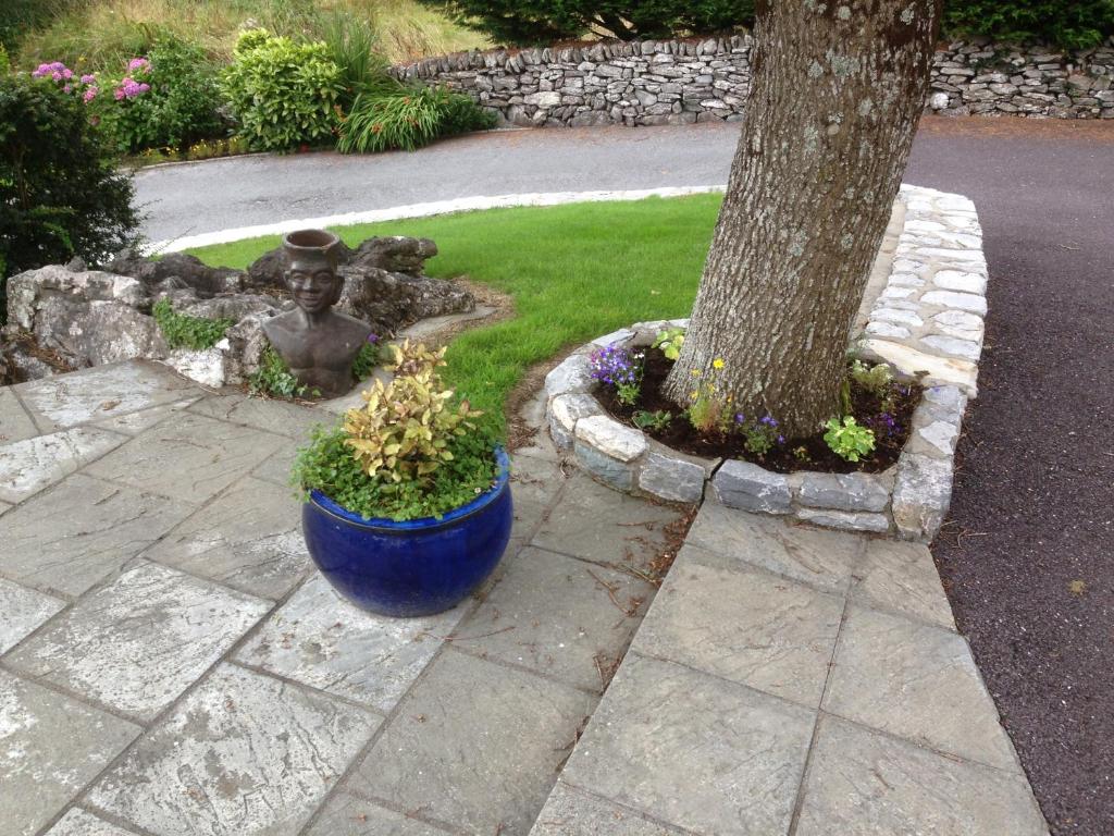 a blue pot next to a tree with a statue at Rockcrest House in Kenmare