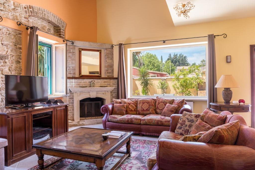 a living room with couches and a tv and a fireplace at Moraitis Mansion in Corfu