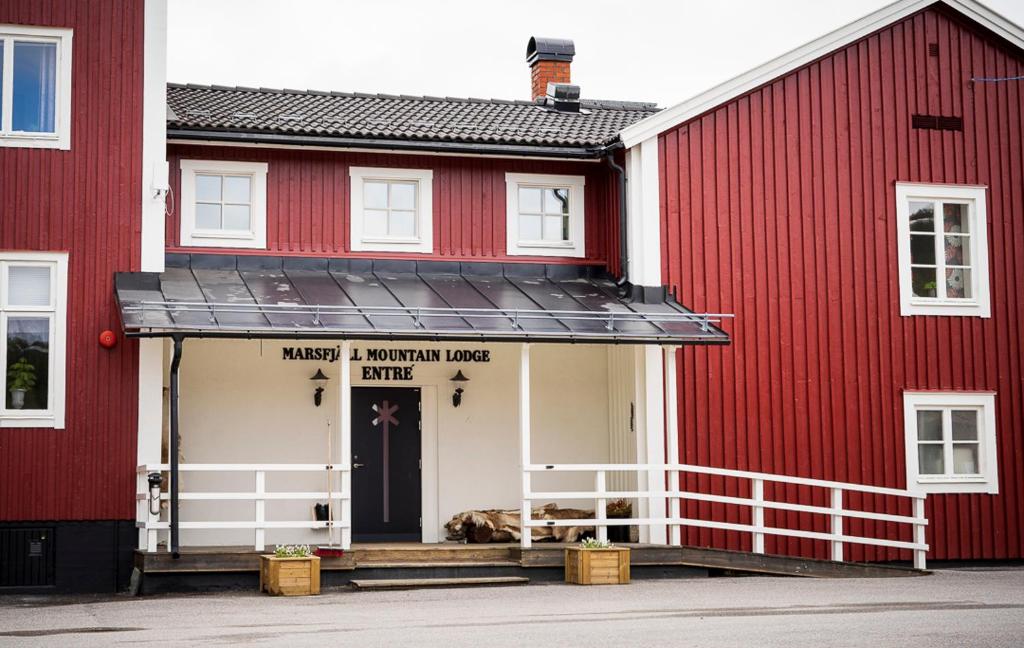 a dog laying on the porch of a red building at Marsfjäll Mountain Lodge Hotell in Saxnäs