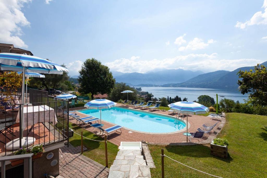 a large swimming pool with chairs and umbrellas at Residence Celeste Lake View Apartments in Mezzegra