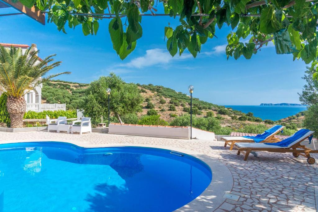 una piscina con sillas y vistas al océano en Villa Palma, en Sitia