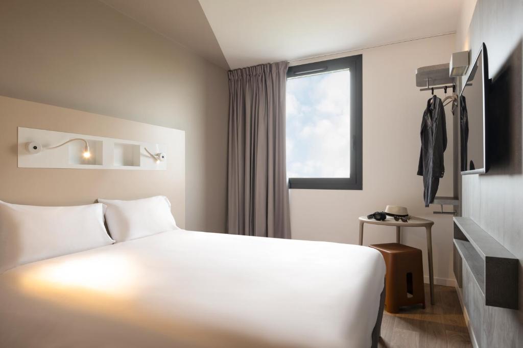 a hotel room with a white bed and a window at ibis budget Gonesse in Gonesse