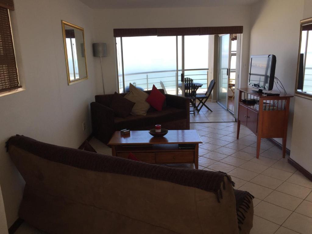 a living room with a couch and a table and a television at Ocean View B1001 in Bloubergstrand