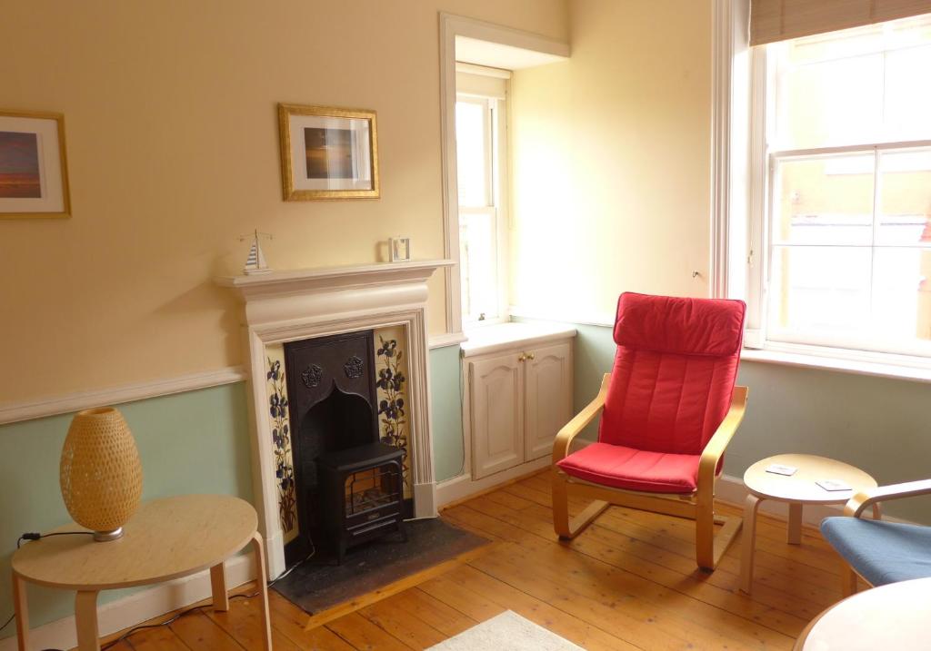 a living room with a red chair and a fireplace at Beach View in North Berwick