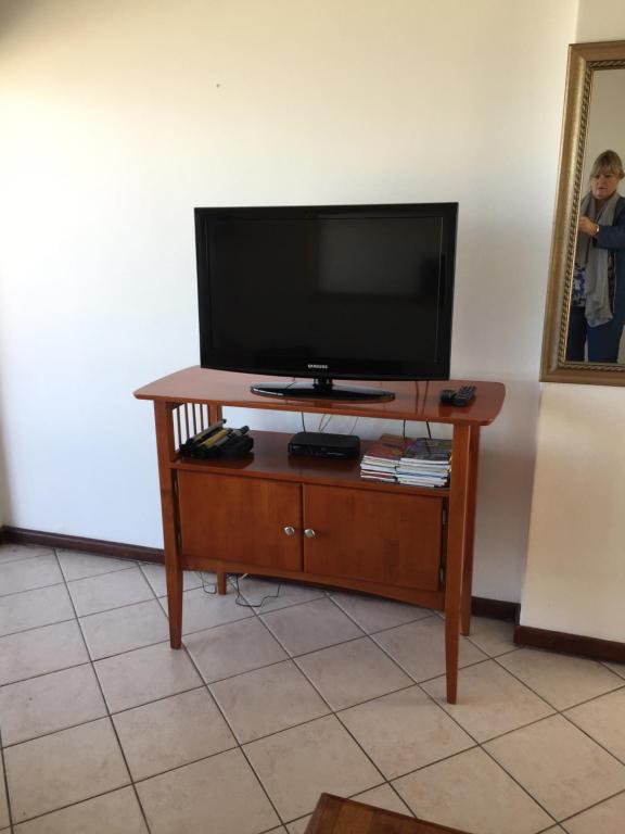 a flat screen tv sitting on top of a wooden entertainment center at Ocean View B1001 in Bloubergstrand