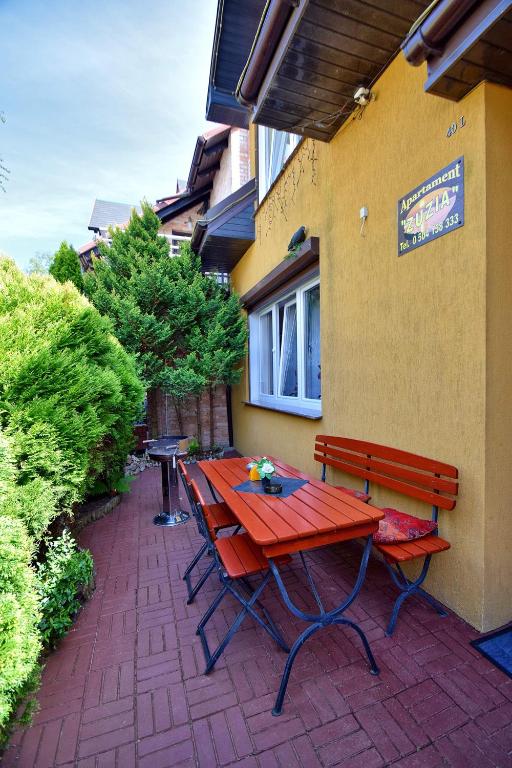 czerwony stół piknikowy i ławka na ceglanym patio w obiekcie Apartament Zuzia w Dźwirzynie