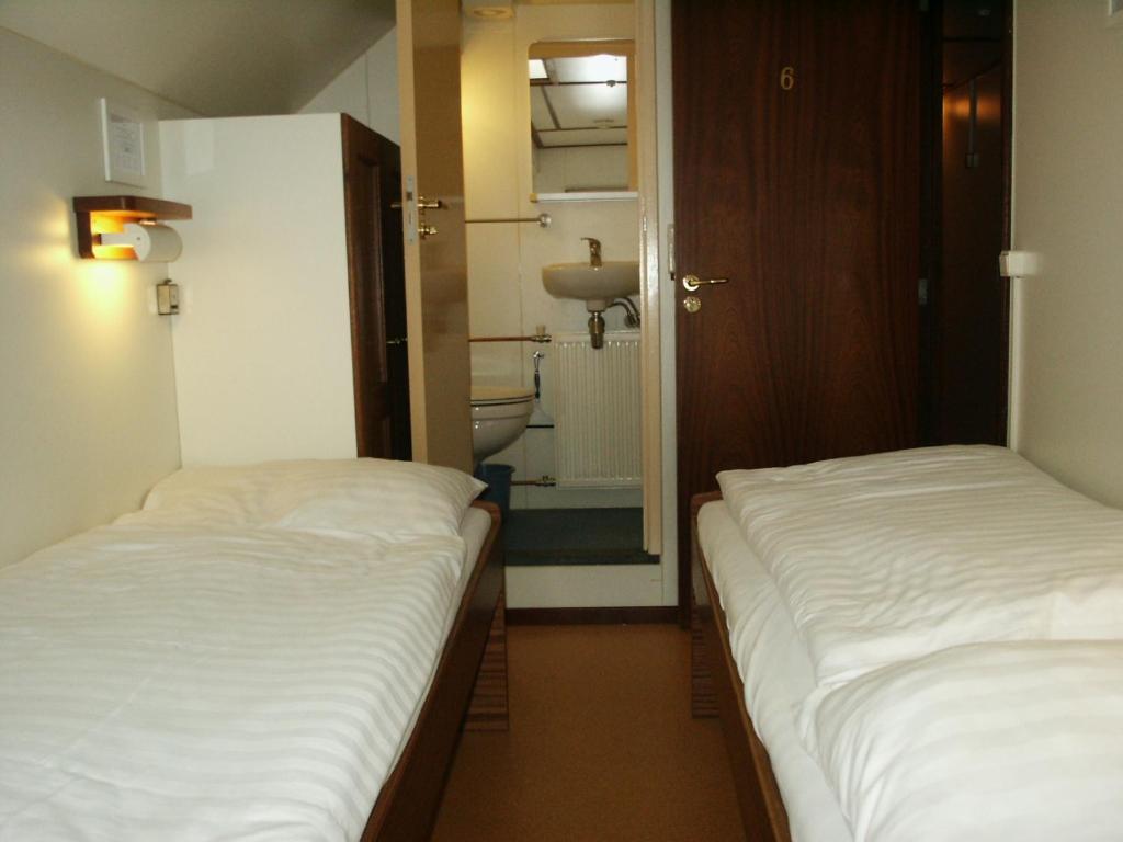 two beds in a small room with a bathroom at Felicitas in Amsterdam