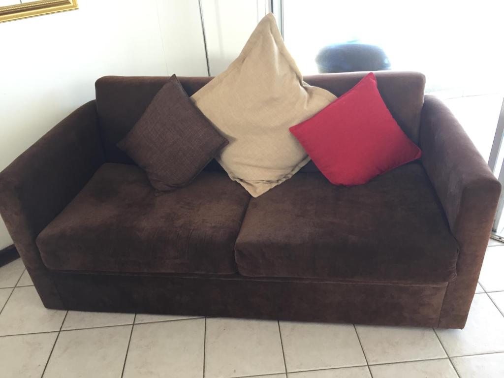 a brown couch with pillows on top of it at Ocean View B1001 in Bloubergstrand