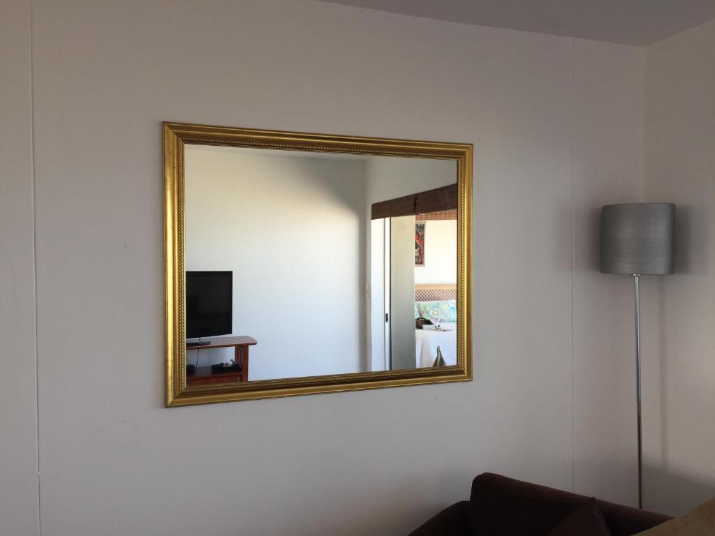 a mirror on a wall with a couch and a television at Ocean View B1001 in Bloubergstrand