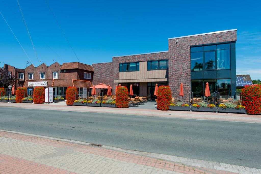 un bâtiment situé dans une rue avec des fleurs devant elle dans l'établissement Landhotel Butjadinger Tor, à Nordenham