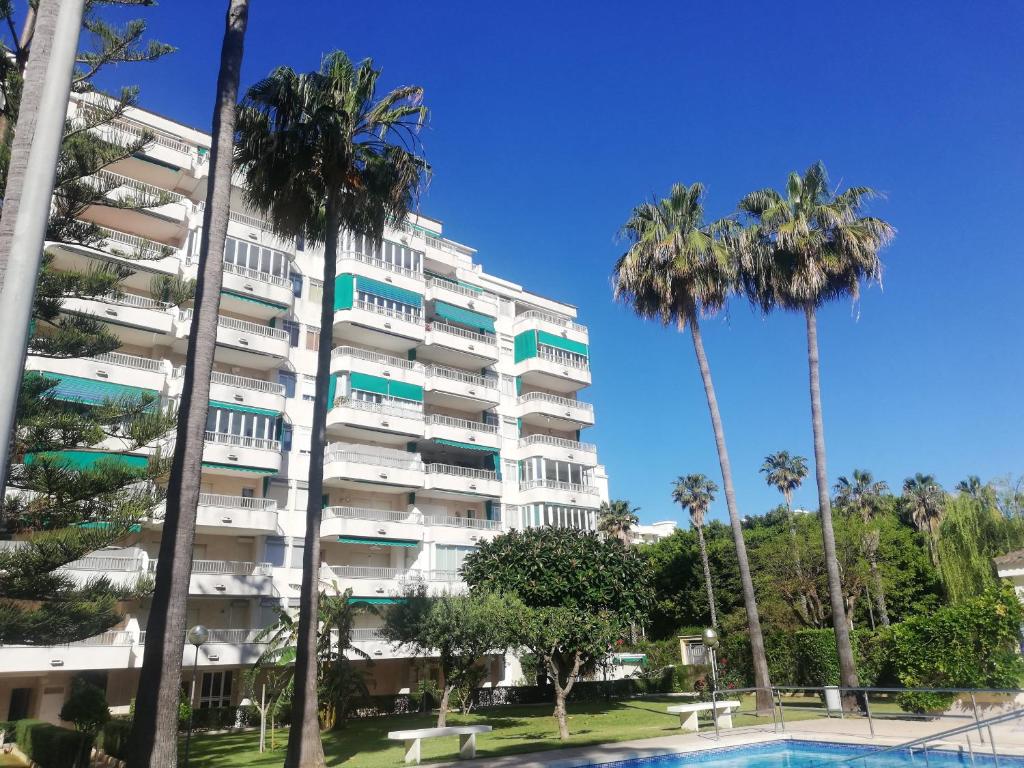 a large apartment building with palm trees and a swimming pool at Parque IV Solo Familias Serviplaya in Gandía