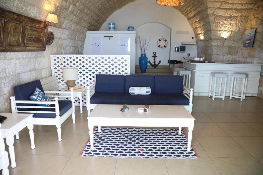 a living room with a couch and tables and a kitchen at Le Blanc Bleu in Jbeil