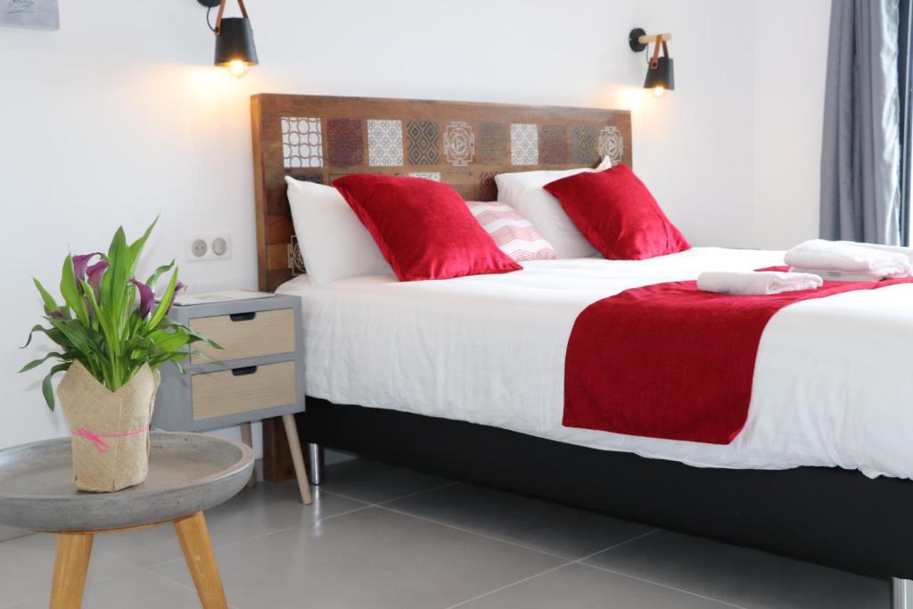 a bedroom with two beds with red pillows and a table at Hotel Fazio in Bonifacio