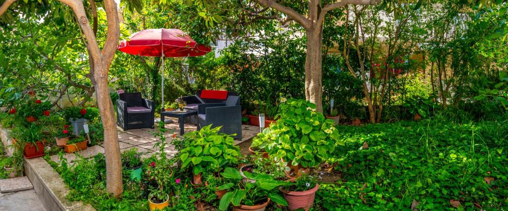 a garden with a red umbrella and chairs and plants at Apartments Emi in Split