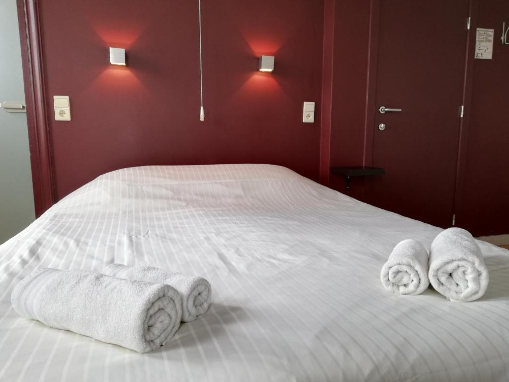 a bed with three rolled towels on it at Logies Het Maantje in De Panne