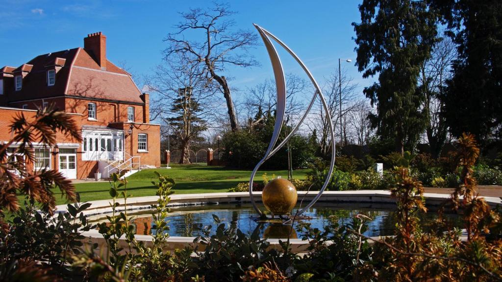 una fuente frente a una casa con un edificio en The Pinewood Hotel, en Slough