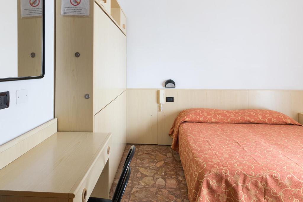 a bedroom with a bed and a desk and a window at Hotel Sabrina in Sottomarina