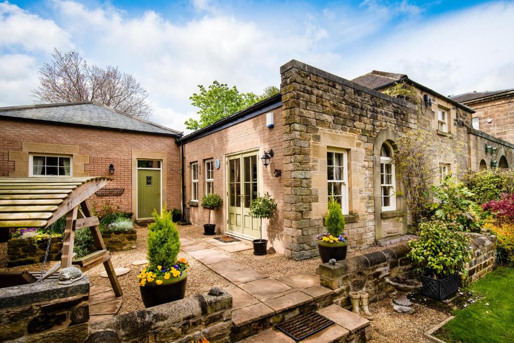 uma antiga casa de tijolos com um pátio com vasos de plantas em Coach House B & B em Alnwick