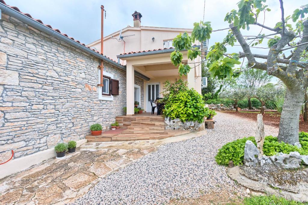 a house with a stone wall and a wooden staircase at Haus Glavani in Barban