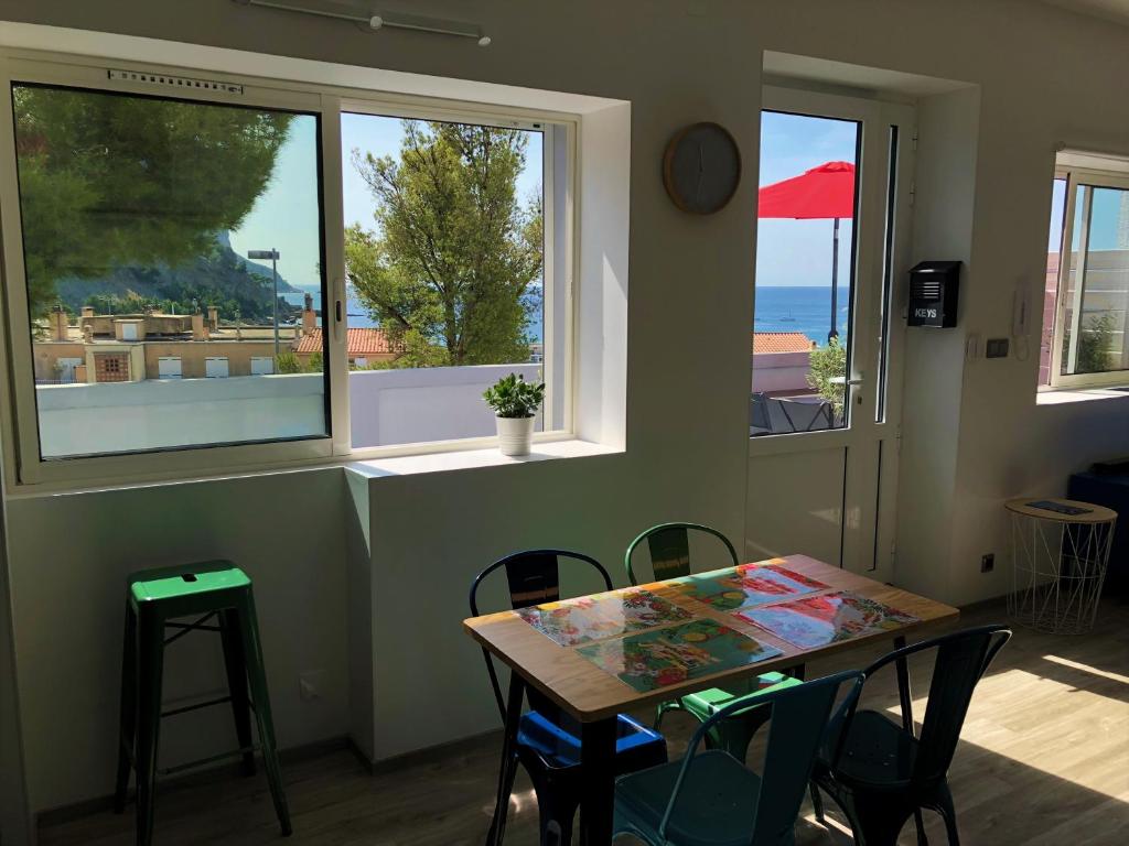 a dining room with a table and chairs and windows at SunRise Cassis in Cassis