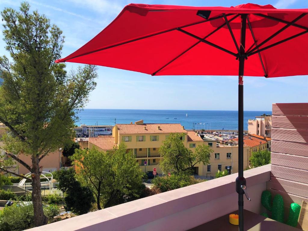 a red umbrella on a balcony with a view of the ocean at SunRise Cassis in Cassis