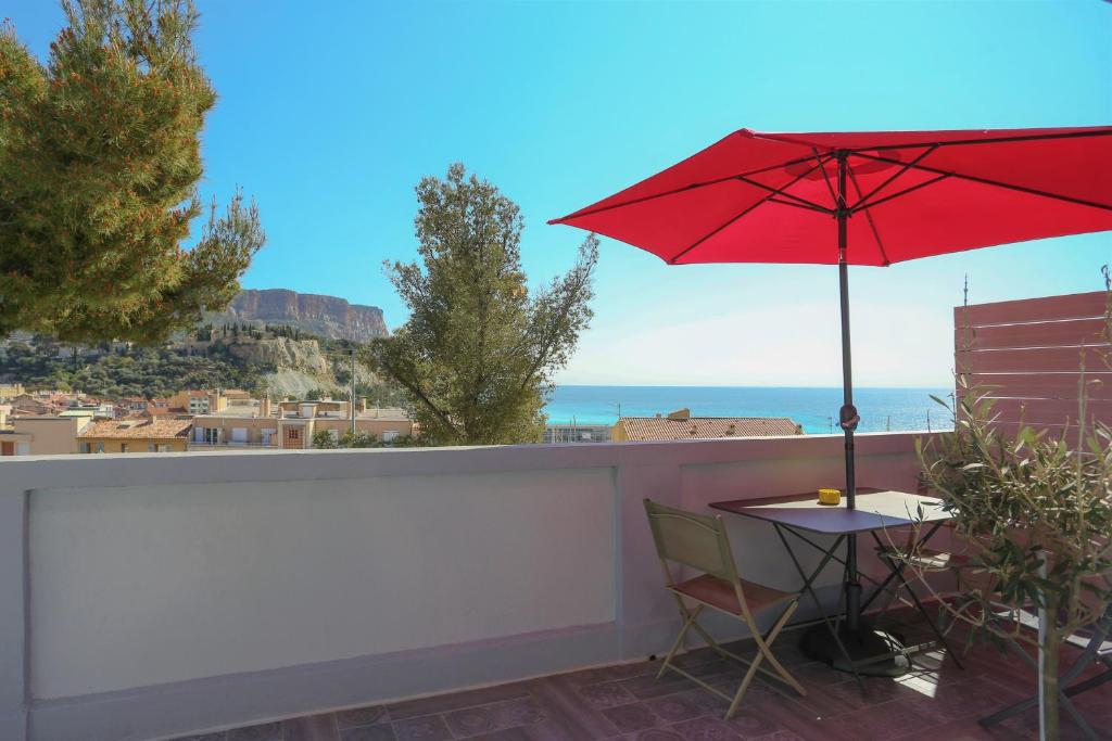 un ombrellone rosso e un tavolo sul balcone di SunRise Cassis a Cassis