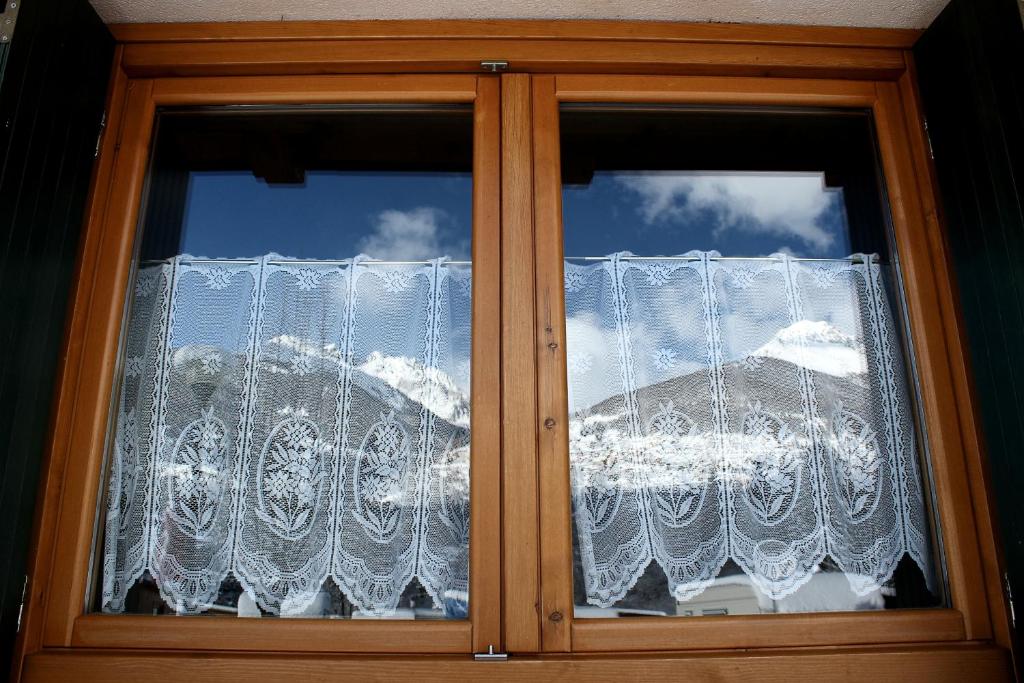 a window with lace curtains on a house at Chalet Presanella in Temù