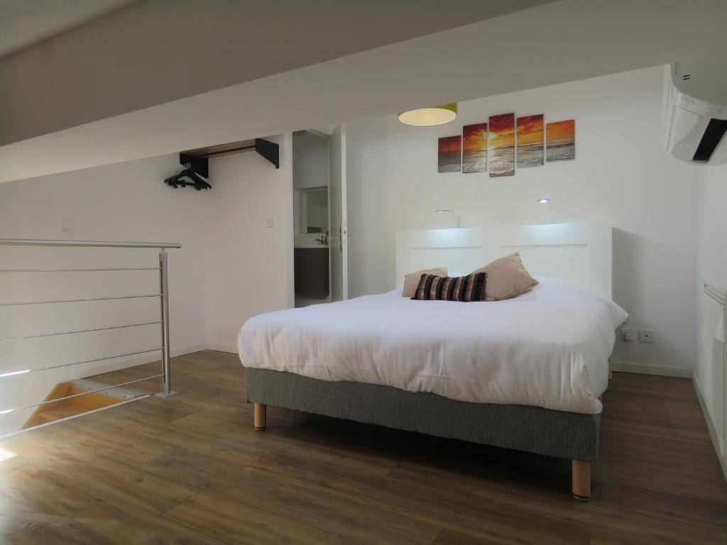 a bedroom with a bed with white sheets at Appartement centre historique avec Terrasse au porte de la Camargue in Saint-Gilles