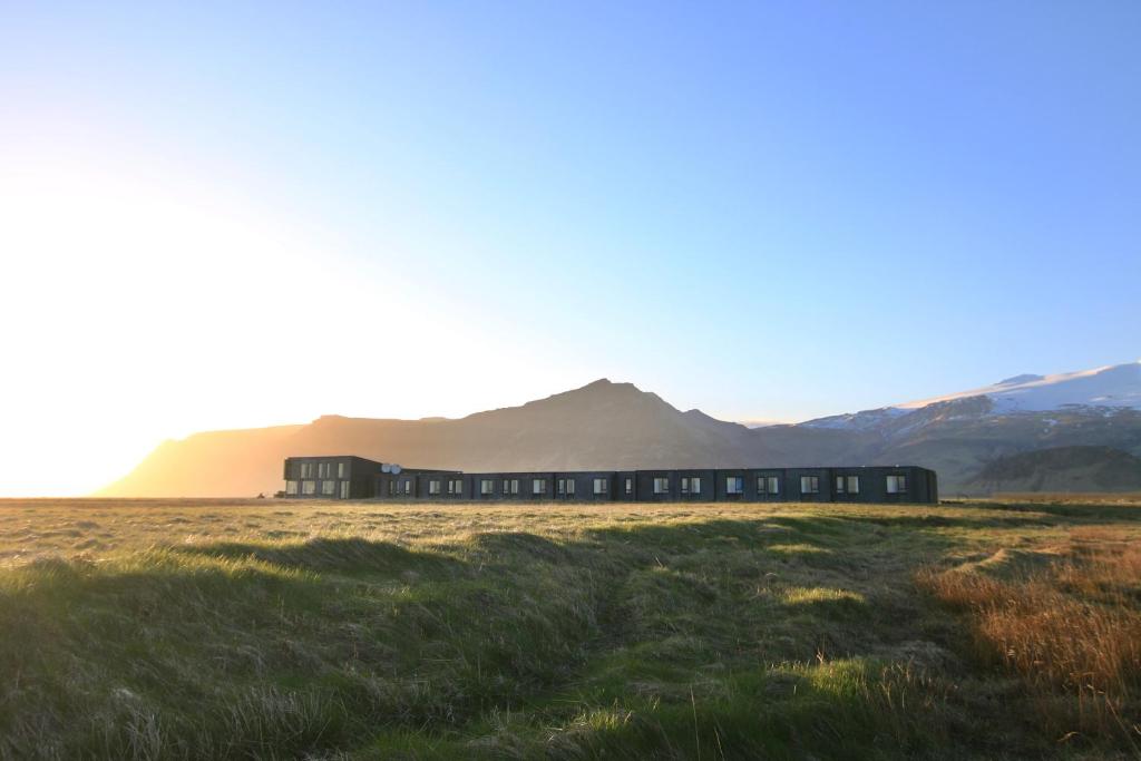 un treno in un campo con montagne sullo sfondo di Umi Hotel a Skogar